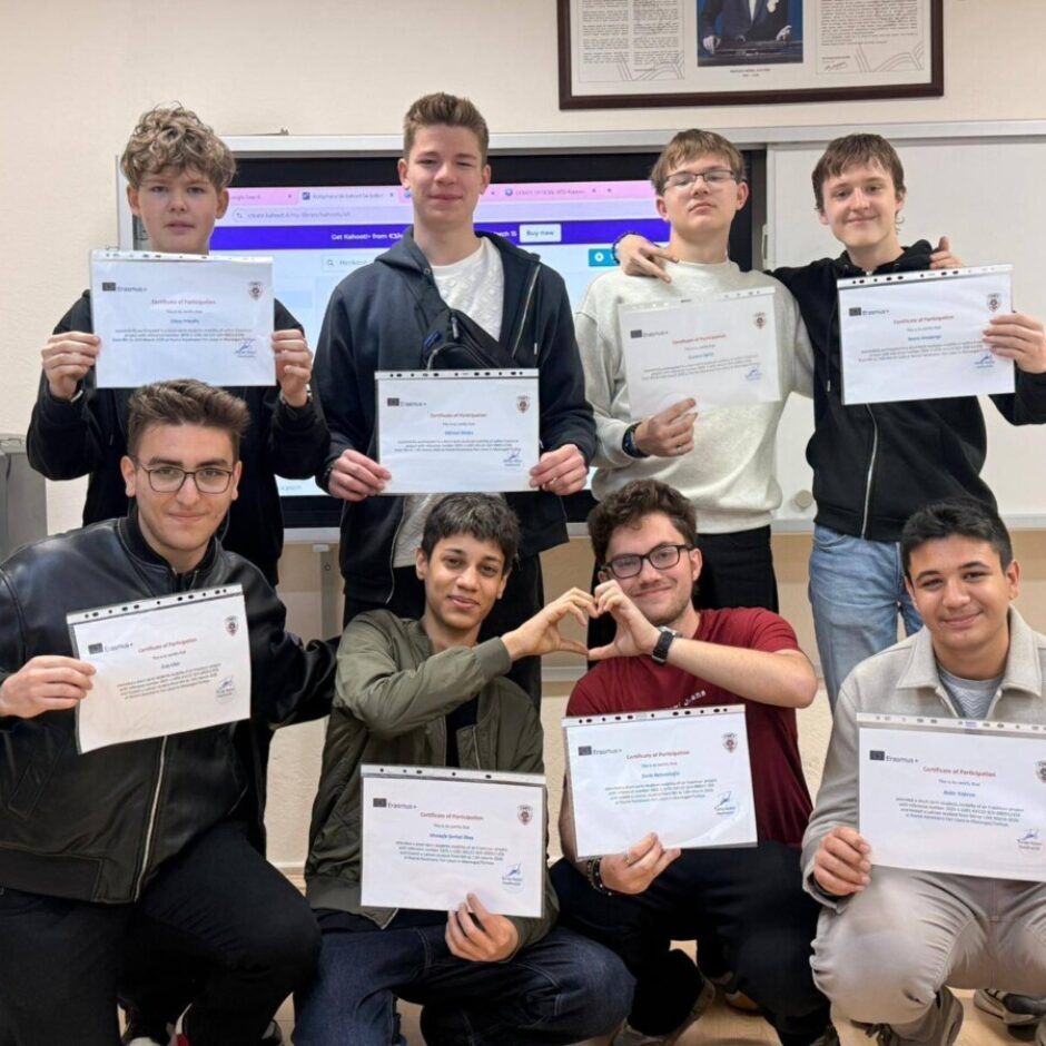 Astoņi jaunieši mācību telpā, daži stāvot, citi tupus, katrs tur rokas priekšā Erasmus+ 